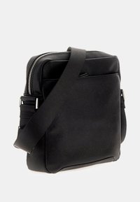 Bolso bandolera negro hecho de material sintético texturizado, con cierre de cremallera, correa ajustable y una forma rectangular elegante.