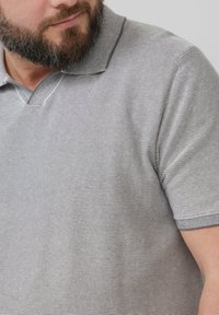 Grijs gestreepte polo shirt met een V-hals en korte mouwen. De stof lijkt glad met een subtiele textuur en contrasterende kraagaccenten.