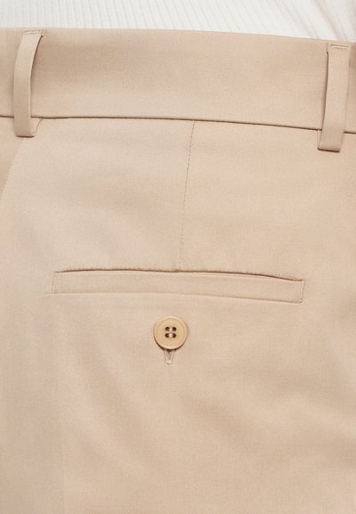 Beige Hose mit glatter Textur, einer genähten Gesäßtasche und einer einzelnen Knopfverschluss. Einfaches und funktionales Design.