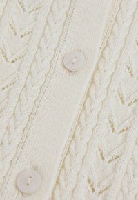 Cardigan in maglione color crema con design a treccia testurizzata, pannello a costine verticale e due bottoni con finitura lucida.