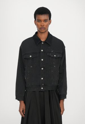 Black denim jacket with a collar, front buttons, two chest pockets, and slight paint splatter details. Features a cropped design and long sleeves.
