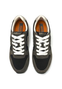 Zapatillas deportivas con un diseño de malla negra, acentos de ante gris y cordones blancos. Suela interior naranja y etiqueta de la marca visibles.