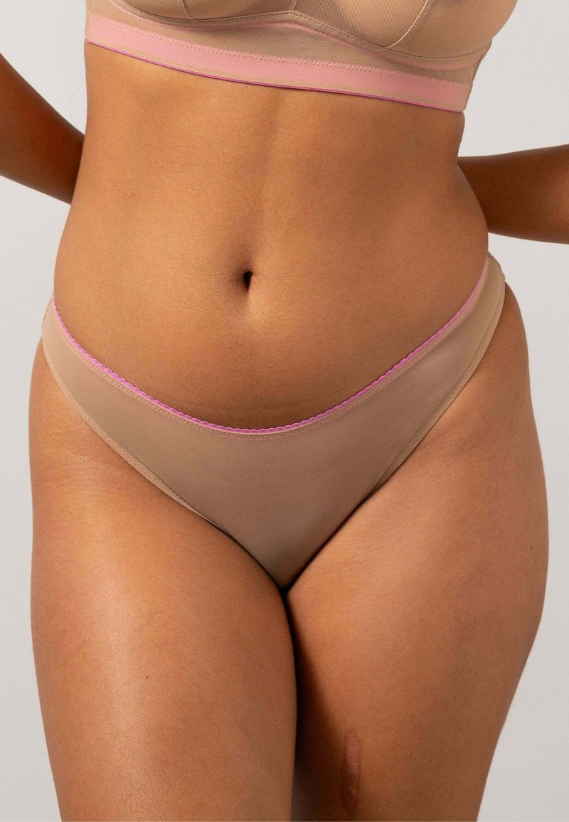 Beige stringtrosor i en slät textur, med en rosa skålad kant längs midjan. Minimalistisk design, lågt skuren form.