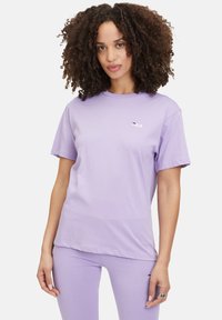 T-shirt viola chiaro a maniche corte con collo rotondo e logo Fila. Tessuto morbido con vestibilità comoda; indossato con leggings abbinati.