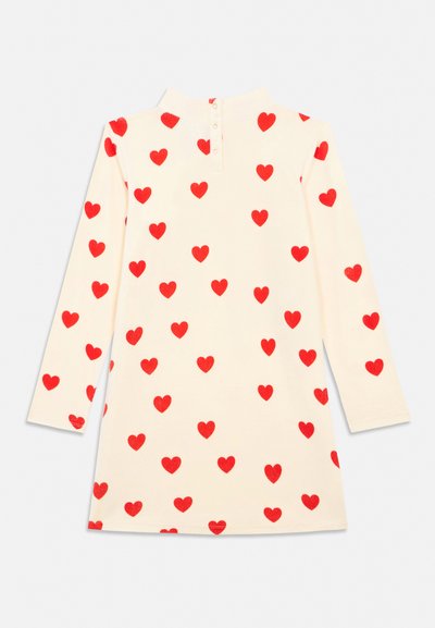 Rochie cu mâneci lungi, de culoare crem, cu guler înalt și model cu inimi roșii dispersate uniform pe material.