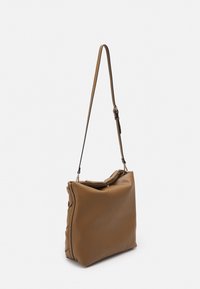 Brązowa skórzana torba na ramię z regulowanym paskiem, miękką fakturą, lekko zaokrąglonym kształtem i górnym złożonym designem.