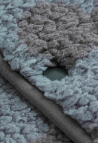 Tejido texturizado en azul claro y gris oscuro con una superficie suave, que presenta un corte circular y un borde suave en gris oscuro.