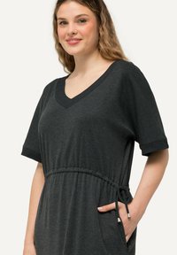 Robe gris foncé avec un décolleté en V, des manches courtes et une taille élastique. Elle possède un cordon de serrage avec des accents métalliques et des poches latérales.