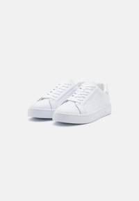 White sneakers featuring a smooth leather upper, round toe, lacing system, and a textured rubber sole with minimal accents.