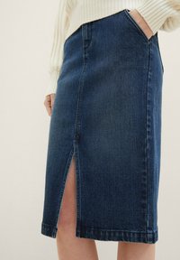 Falda lápiz de mezclilla en azul oscuro con una abertura frontal, que cuenta con bolsillos laterales y un dobladillo con detalles de costuras visibles.