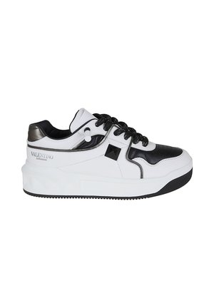 Sneaker Valentino Garavani bianco e nero con lacci neri, dettaglio borchie e suola spessa bianca, mostrato dalla parte esterna.