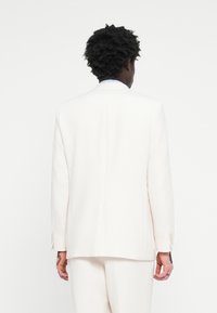 White tailored suit jacket with a notch lapel, single vent, and buttoned cuffs. Smooth fabric with a structured silhouette.