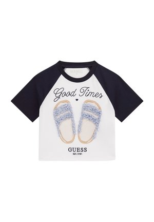 Camiseta blanca de manga corta con mangas marino, que presenta un estampado gráfico de sandalias azules y el texto "Buenos Momentos". Material de algodón, corte relajado.