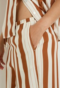 Set di tessuto a righe marroni e crema composto da una camicia con bottoni dal taglio morbido e pantaloni abbinati con elastico in vita e tasche laterali.