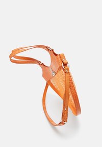 Sac à main orange avec une texture crocodile, un corps en maille et des sangles ajustables. Équipé de quincaillerie en métal et d'un design structuré et ouvert.