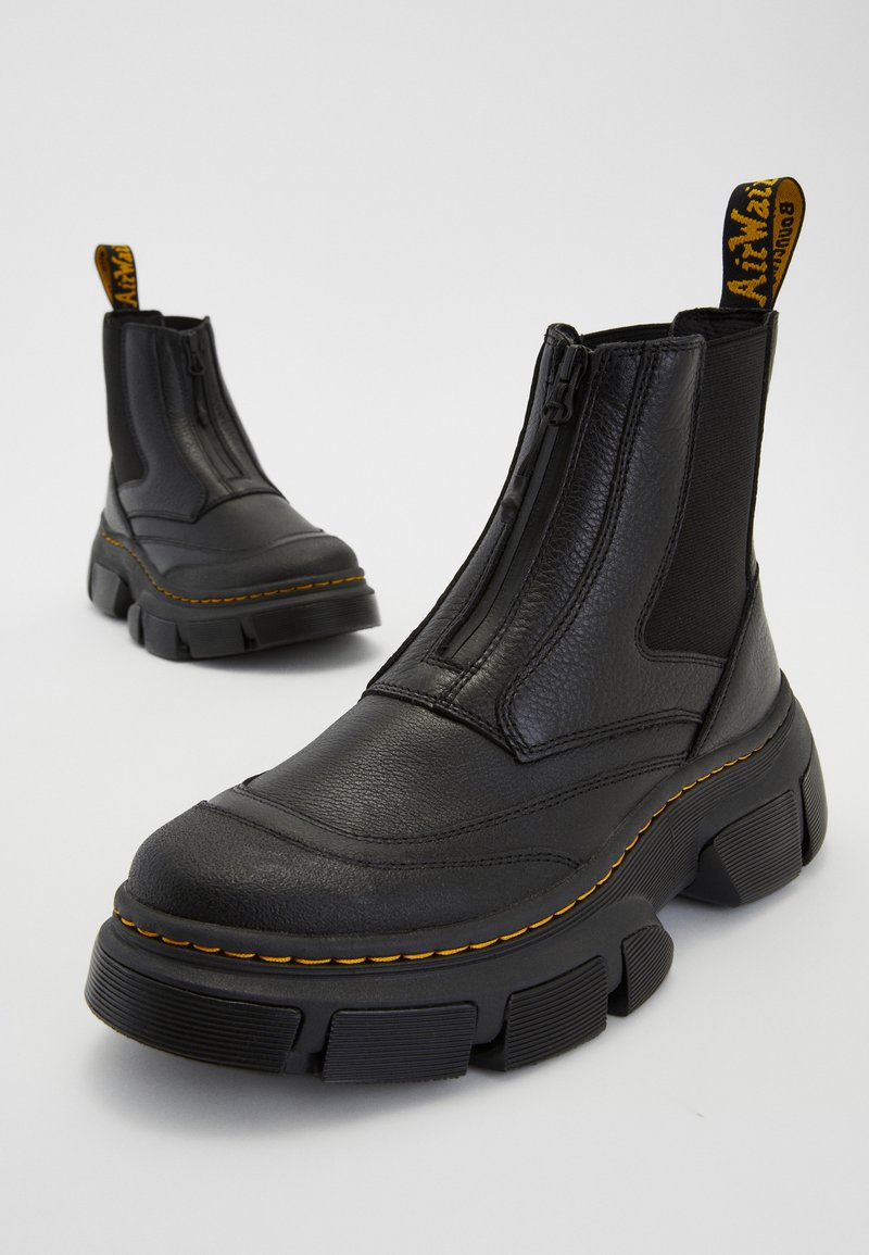 Stivali neri alla caviglia in pelle texturizzata, con cerniera laterale, pannelli elastici e suole spesse in gomma con dettagli di cucitura gialla.