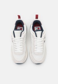 Zapatillas de malla blanca y ante con acentos en azul marino, una etiqueta roja en el talón y cordones blancos. Cuenta con un forro interior con un diseño estampado.