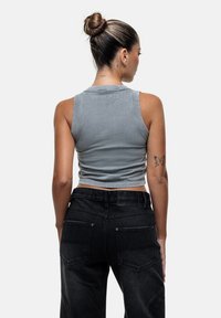 Grijze, cropped tanktop met bredere banden, voorzien van een gladde textuur en een ronde halslijn, gecombineerd met hoge zwarte denim jeans.
