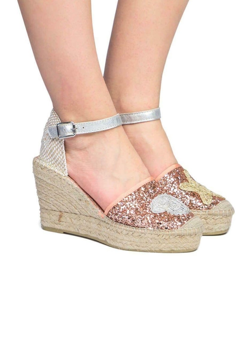 Espadrilles compensées avec devant scintillant en or rose, patchs brodés, brides d'argent à la cheville et semelles plateformes en jute tissée sur pieds nus.