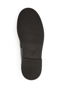 Schwarze Schuhsohle mit einer strukturierten Oberfläche, flaches Design, abgerundete Spitze und leichter Absatz. Herkunfts- und Größenangaben sichtbar.