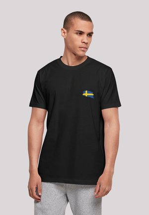 Black cotton T-shirt featuring a small blue and yellow Swedish flag graphic on the left chest area. Classic crew neckline, short sleeves.