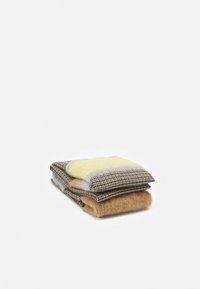 Écharpe en laine pliée avec un motif pied-de-poule beige et marron, présentant des blocs de couleur jaune et beige sur un fond blanc.