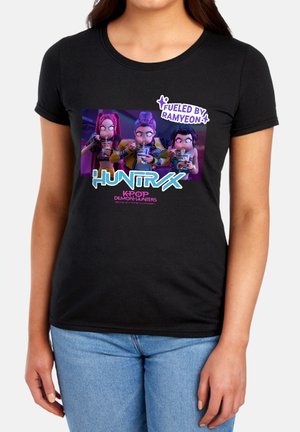 Three animated characters eating ramyeon with text "Fueled by Ramyeon," "HUNTRX," and "K-Pop Demon Hunters" on a black t-shirt.