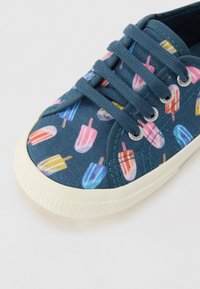 Sneaker in tela blu con un motivo di gelati colorati, suola in gomma bianca, punta rotonda e lacci blu a contrasto.