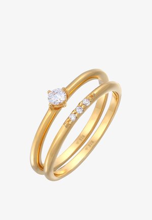 Gouden ringenset met twee banden: één met een grote centrale heldere steen en de andere met drie kleinere heldere stenen. Gladde afwerking.