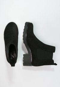 Czarne botki za kostkę z fakturowaną cholewką i elastycznymi bokami, z masywnym obcasem i gładką czarną podeszwą.