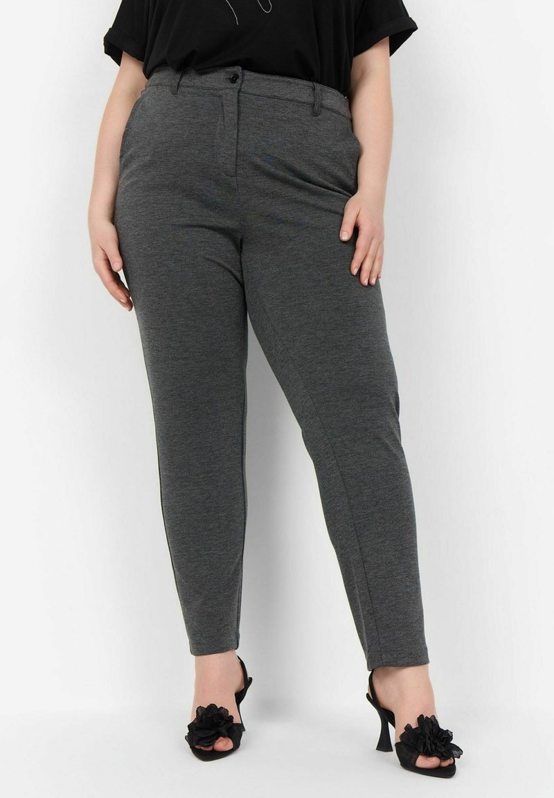 Pantalons tailleur gris anthracite avec devant plat, fermeture à bouton et poches latérales. Associés à des talons ouverts noirs avec des accents floraux.