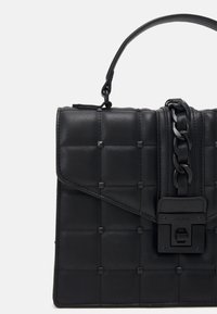 Czarna pikowana skórzana torebka z uchwytem u góry, detalem z łańcuszka i metalowym zapięciem.