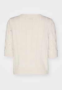 Krémový pletený svetr s krátkými rukávy, zdobený kabelovými vzory a malými dekorativními perlami na rukávech.