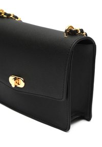 Mustast nahast käekott, millel on kuldne pöörelukk ja kett-õlapael, mille kaudu on põimitud must nahk.