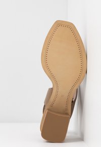Semelle d'une chaussure beige pour femme avec couture décorative et talon bloc, taille 37, sur fond blanc d'angle.