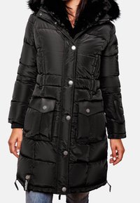 Černý péřový kabát s kapucí lemovanou kožešinou, zapínáním na patentky, velkými předními kapsami a žebrovanými manžetami. Má prošívaný design a nastavitelný lem.