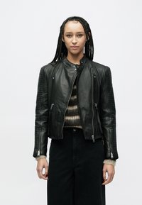 Czarna skórzana kurtka motocyklowa o dopasowanym kroju, z żebrowanymi akcentami na rękawach oraz zamkami błyskawicznymi z przodu i na mankietach.