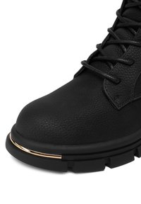 Melnas ādas potītes zābaki ar teksturētu apdari, ar apaļu purngalu, melniem šņorēm un zelta akcentu uz zoles malas.