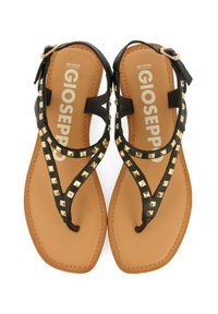 Sandalias negras con un diseño de tira en T, tachuelas doradas en forma de pirámide y una plantilla color tostado. Las correas están hechas de un material texturizado, aseguradas con un hebilla para el tobillo.