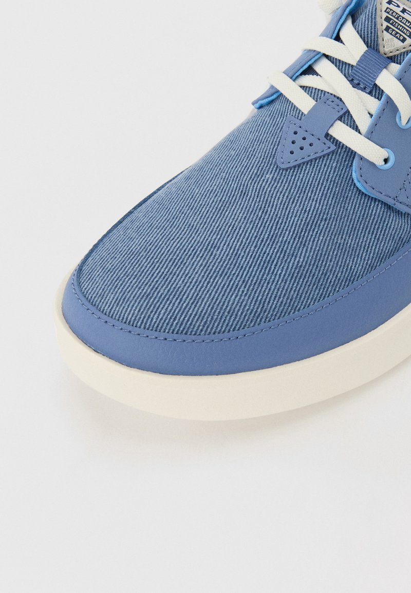 Niebieskie trampki z płóciennym wierzchem, teksturowaną powierzchnią, gładkimi skórzanymi akcentami, białymi sznurowadłami oraz jasnobeżową gumową podeszwą.