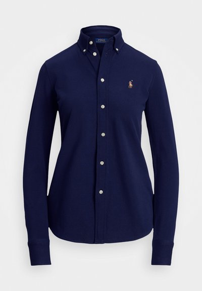 Camisa de manga larga de algodón en color naval. Presenta un collar puntiagudo, botones en la parte delantera y un logo bordado en el pecho.