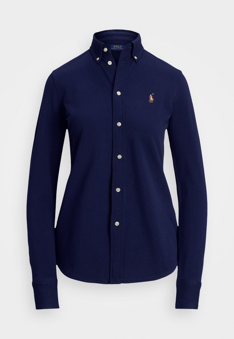 Marineblå langermet skjorte med knapper laget av bomull. Har en spiss krage, knapper foran og et brodert logo på brystet.