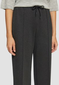 Dunkelgraue, locker sitzende Hose aus weichem Stoff, mit einem elastischen Bund und Kordelzug sowie mit Vorderfalten.