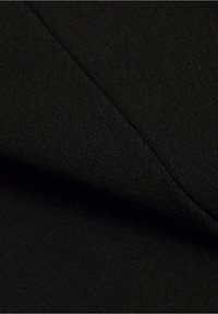 Svart tyg med en strukturerad yta, som har en lätt lyster och diagonala veck. Slät yta med subtila sömnadsdetaljer.