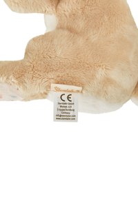 Plush toy in beige with a soft fur texture and white accents, featuring a tag with branding and safety information.