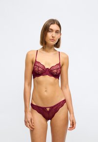 Soutien-gorge en dentelle bourgogne et culotte assortie avec des motifs complexes, des bretelles réglables et un détail découpé sur le devant de la culotte.