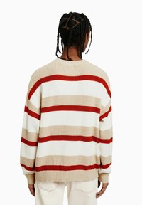 Beige, vit och röd randig stickad tröja med rund hals, ribbade muddar och lös passform. Har en strukturerad tygkvalitet och avslappnad design.