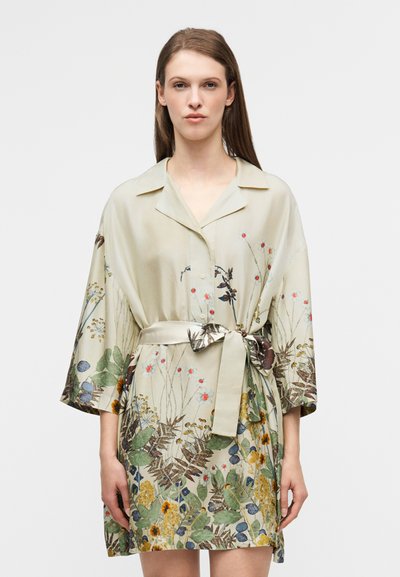 Robe portefeuille à motif floral en beige clair, dotée d'un col et de manches larges, avec une ceinture en tissu et des imprimés botaniques vibrants à l'ourlet.