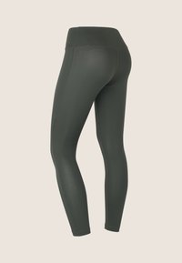 Leggings verde oliva realizzati in tessuto elastico, con una vita alta e design senza cuciture, dotati di cuciture piatte per il massimo comfort.