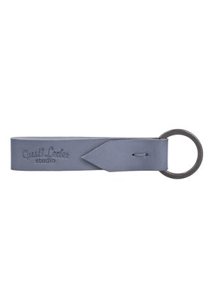 Gray leather keyring with metal ring and "Gusti Leder studio" embossed on the strap, featuring a pointed leather end looped through the ring.